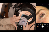 Close-up of a person's eye being photographed with a phone through a ring light.