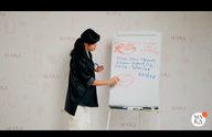 Woman in a black jacket writing on a flip chart with lip illustrations and notes.