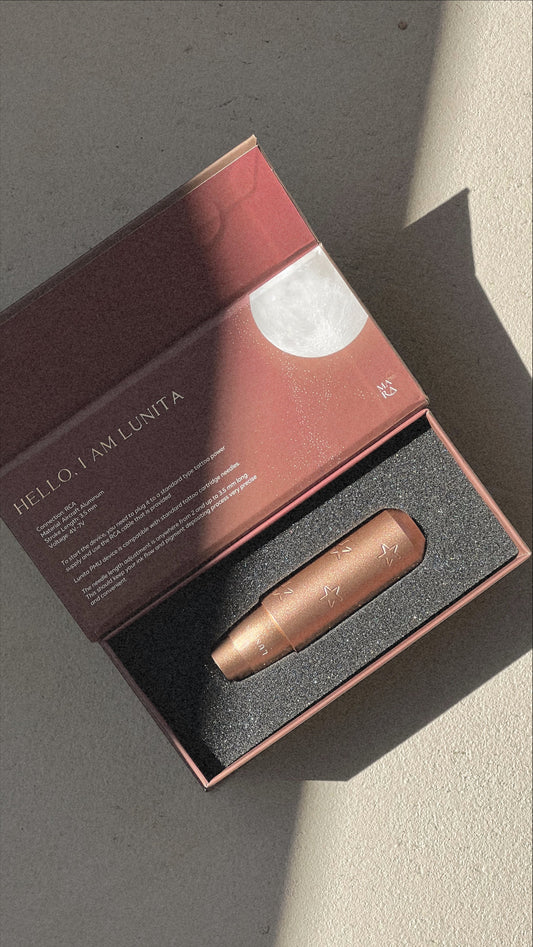 Rose gold skincare device in a brown box with a text description on a light background.
