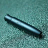 Black, cylindrical object resting on a textured, dark green surface.