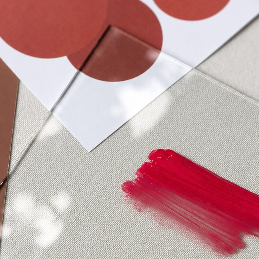 Two coral pigment drops blending smoothly on a white palette