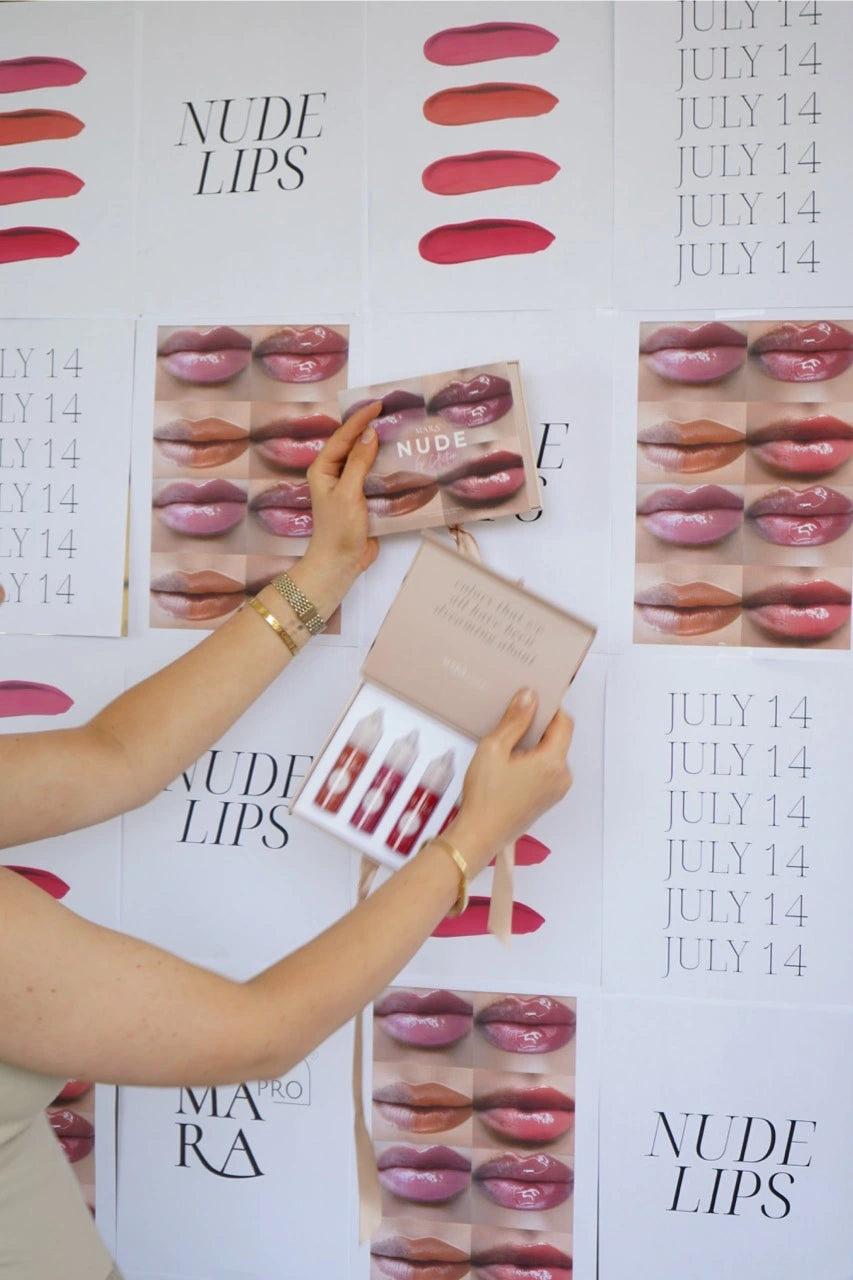 Artist holding the NUDE Collection box against a wall of lip swatches