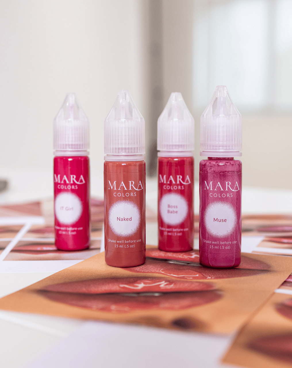 The four MARA PRO NUDE Collection pigment bottles standing on printed lip swatch photos