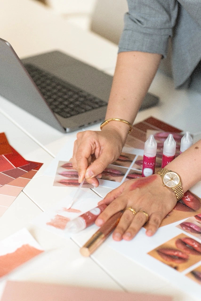 Artist and client comparing pigment swatches on the hand in warm natural light
